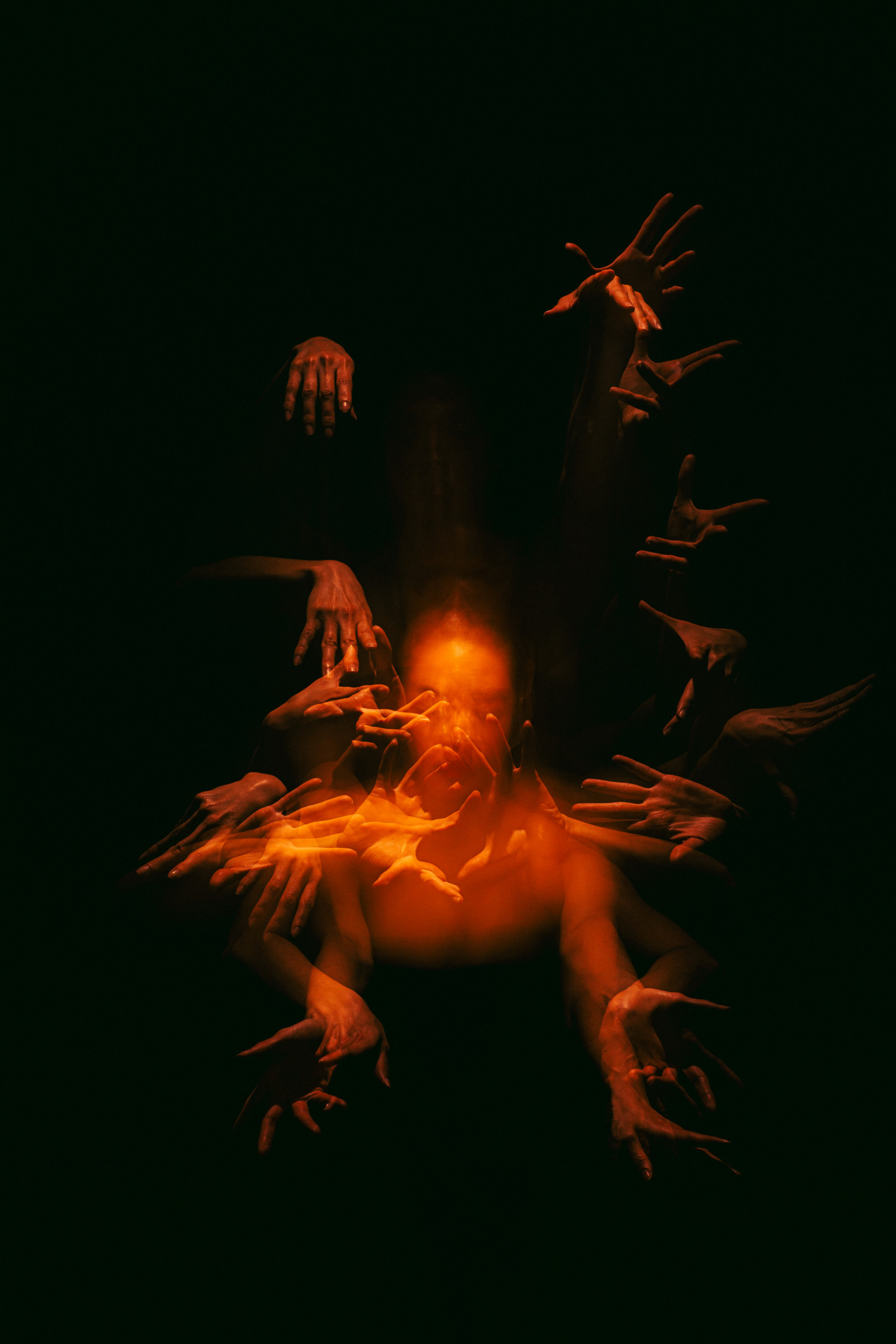 A figure lit in deep orange, reached for by a dozen overlapping hands out of the dark.