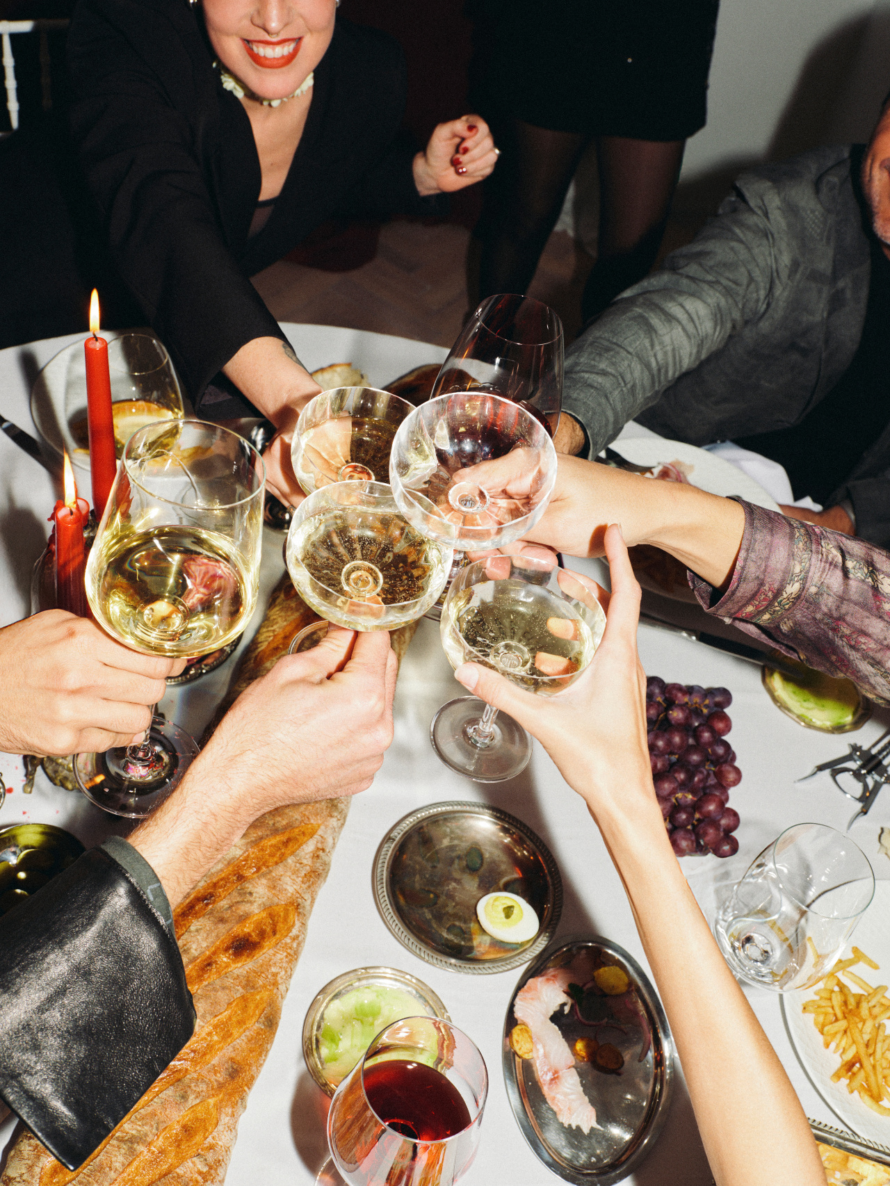 Friends raising their glasses over a candlelit dinner table.